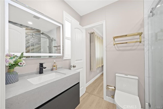 bathroom with a stall shower, visible vents, toilet, wood finished floors, and vanity