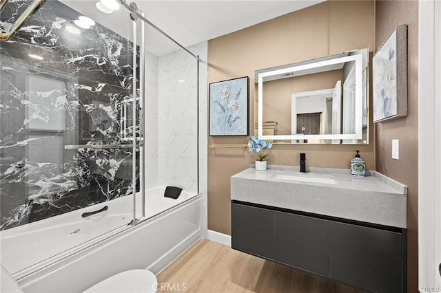 bathroom with wood finished floors, vanity, and bath / shower combo with glass door