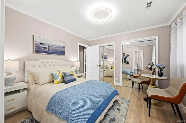 bedroom with multiple closets, visible vents, crown molding, and light wood-style flooring