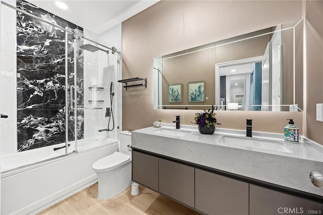 bathroom featuring toilet, double vanity, bath / shower combo with glass door, and a sink