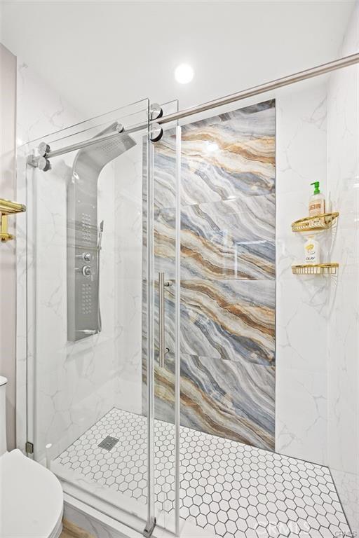 full bathroom with toilet and a marble finish shower