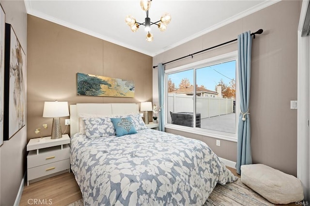 bedroom with a chandelier, baseboards, wood finished floors, and crown molding