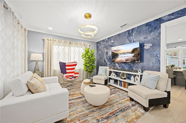 living area featuring a chandelier, crown molding, wood finished floors, visible vents, and wallpapered walls