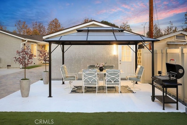 view of patio featuring outdoor dining space, fence, and a gazebo