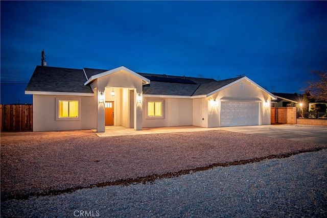 ranch-style home with a garage, solar panels, fence, concrete driveway, and stucco siding