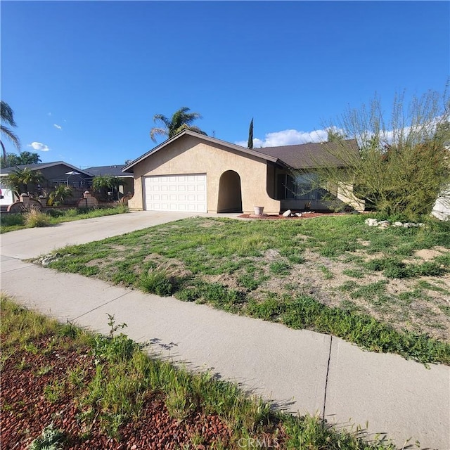 view of front of house with driveway, an attached garage, and stucco siding