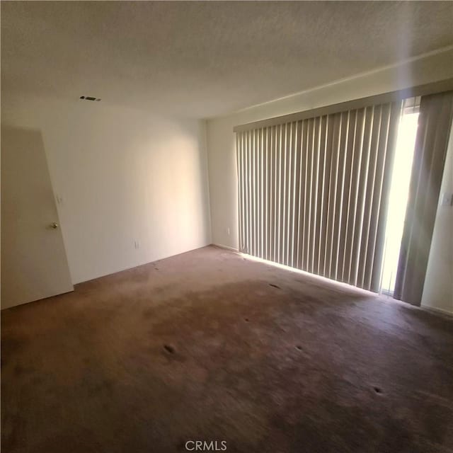 carpeted empty room featuring visible vents and a textured ceiling