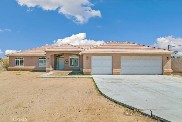 view of front of house featuring a garage, a tile roof, driveway, and stucco siding