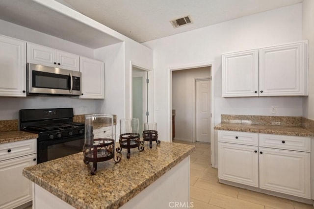 kitchen with white cabinetry, stainless steel microwave, gas stove, and visible vents