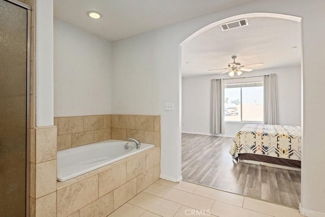 ensuite bathroom featuring tile patterned flooring, visible vents, ceiling fan, a shower with shower door, and a bath