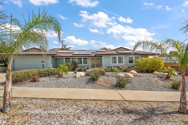 ranch-style house featuring a garage and solar panels