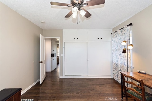 bedroom with a textured ceiling, dark wood-style flooring, a closet, and baseboards