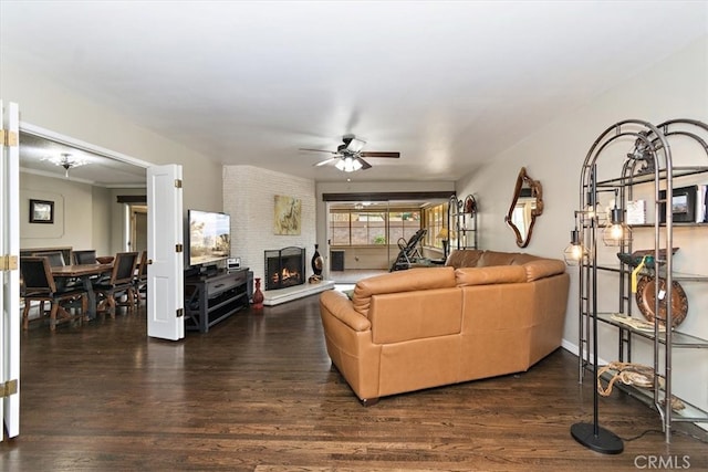 living area with a large fireplace, dark wood-style flooring, and a ceiling fan