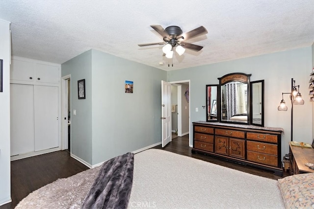 bedroom with a textured ceiling, ceiling fan, dark wood-style flooring, and baseboards