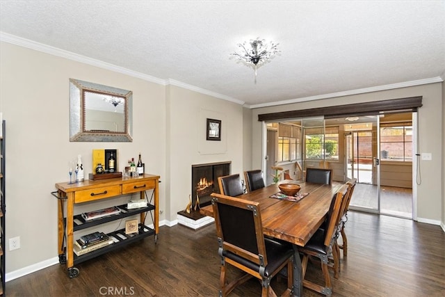 dining space with a lit fireplace, ornamental molding, wood finished floors, and baseboards