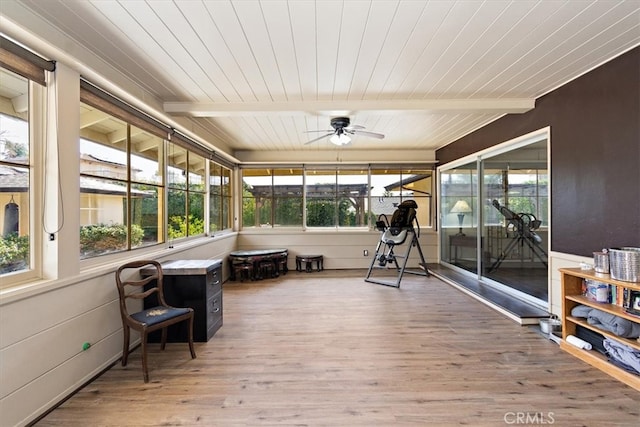 sunroom with a ceiling fan, wood ceiling, beam ceiling, and a healthy amount of sunlight