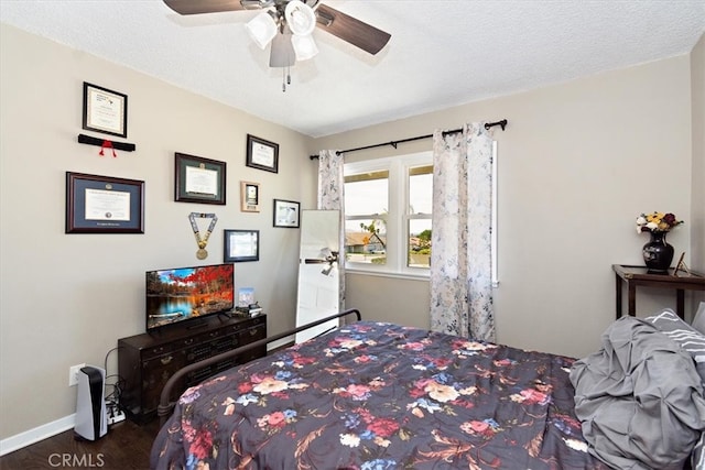 bedroom with a ceiling fan, baseboards, dark wood-type flooring, and a textured ceiling