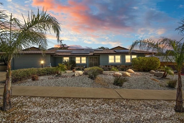 view of front of property featuring a garage and roof mounted solar panels