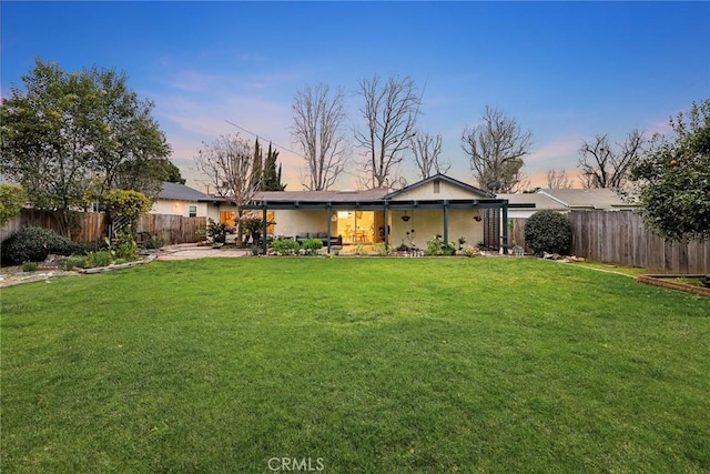 rear view of house with a fenced backyard, a patio, and a yard