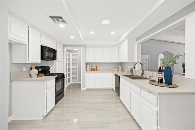 kitchen with visible vents, white cabinets, light countertops, black appliances, and a sink