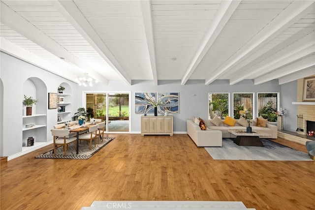 living room with a brick fireplace, baseboards, wood finished floors, and beamed ceiling