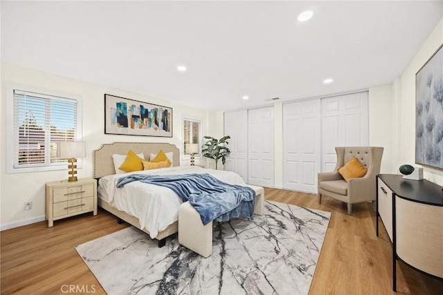 bedroom with baseboards, recessed lighting, wood finished floors, and multiple closets