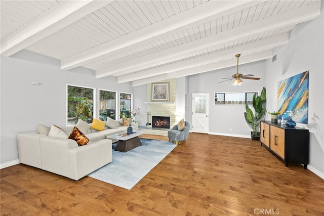 living area with vaulted ceiling with beams, a fireplace, wood finished floors, visible vents, and baseboards