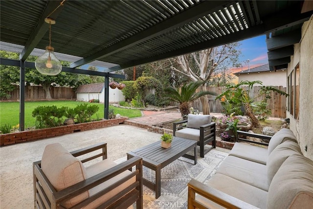 patio terrace at dusk with an outbuilding, a fenced backyard, a storage shed, an outdoor living space, and a lawn