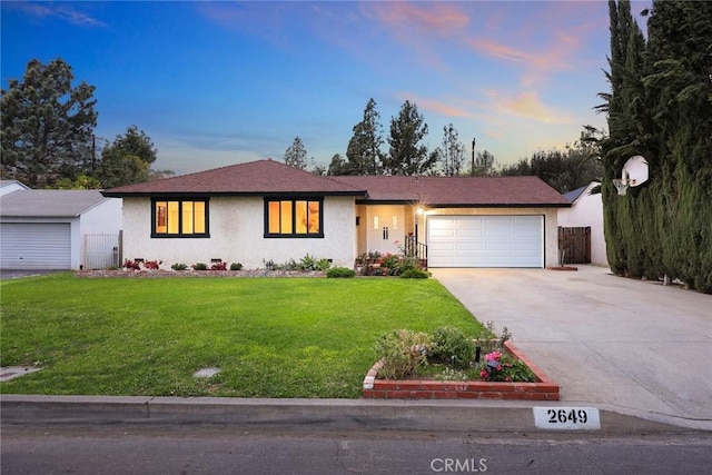 view of front of home featuring a garage, fence, concrete driveway, stucco siding, and a front lawn