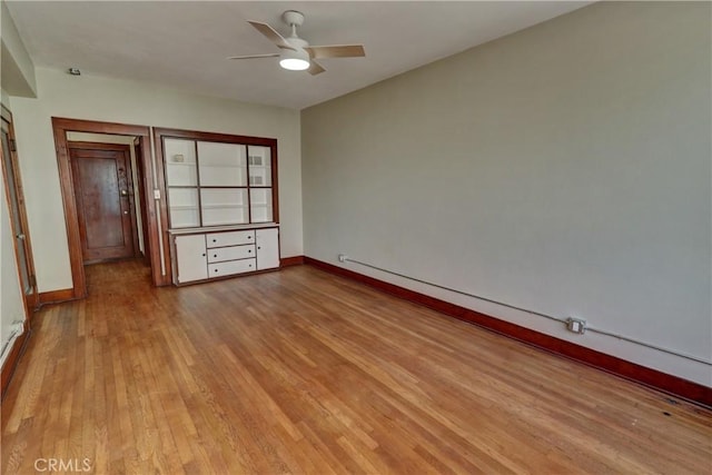 empty room with baseboards, a ceiling fan, and wood finished floors