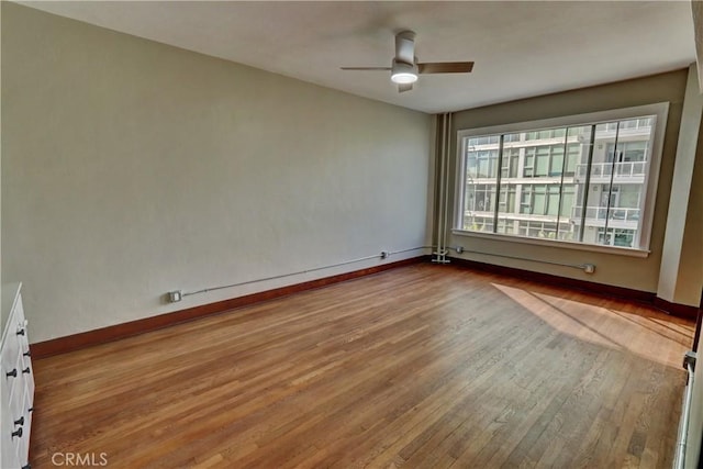 spare room with ceiling fan, baseboards, and wood finished floors