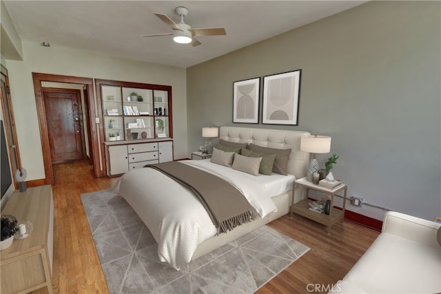 bedroom with a ceiling fan, baseboards, and wood finished floors