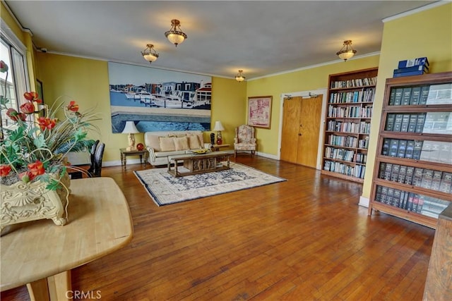 living area with ornamental molding, hardwood / wood-style floors, and baseboards