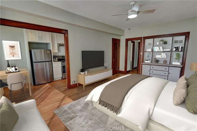 bedroom featuring light wood-type flooring, freestanding refrigerator, and a ceiling fan