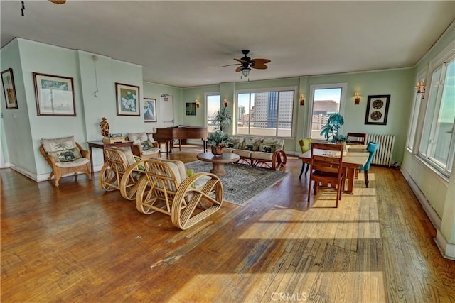 interior space with wood-type flooring, baseboards, radiator heating unit, and a ceiling fan