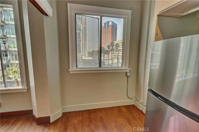 interior space with freestanding refrigerator, baseboards, and wood finished floors