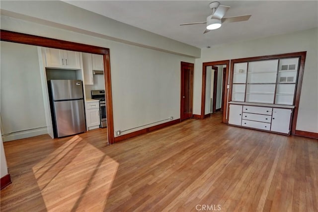 interior space featuring a ceiling fan, a baseboard heating unit, light wood-style flooring, and baseboards