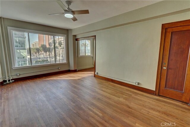 unfurnished room featuring a ceiling fan, baseboards, and wood finished floors