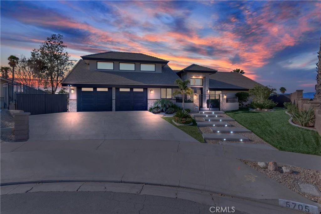 view of front of property featuring a tile roof, stucco siding, fence, stone siding, and driveway