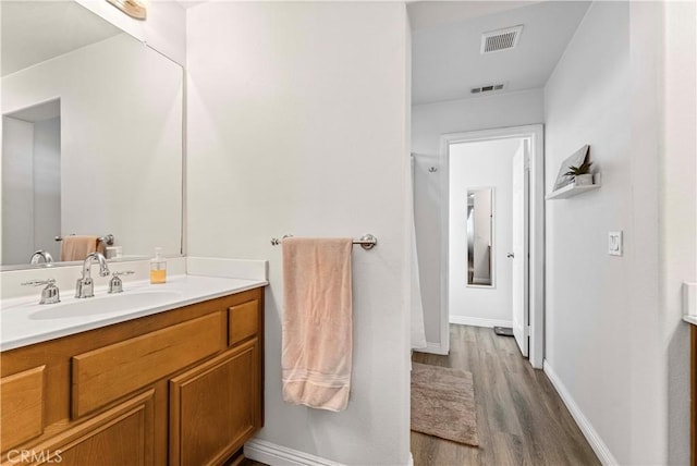 bathroom with wood finished floors, vanity, visible vents, and baseboards