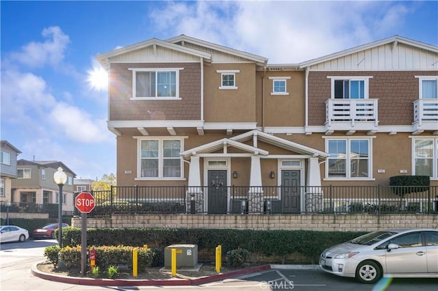 townhome / multi-family property with uncovered parking and stucco siding