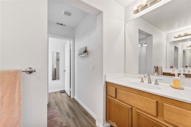 bathroom with vanity, wood finished floors, visible vents, and baseboards