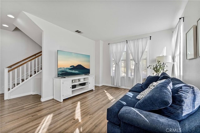 living area with visible vents, baseboards, wood finished floors, stairs, and recessed lighting