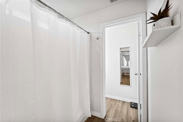 bathroom with a shower with curtain, baseboards, and wood finished floors