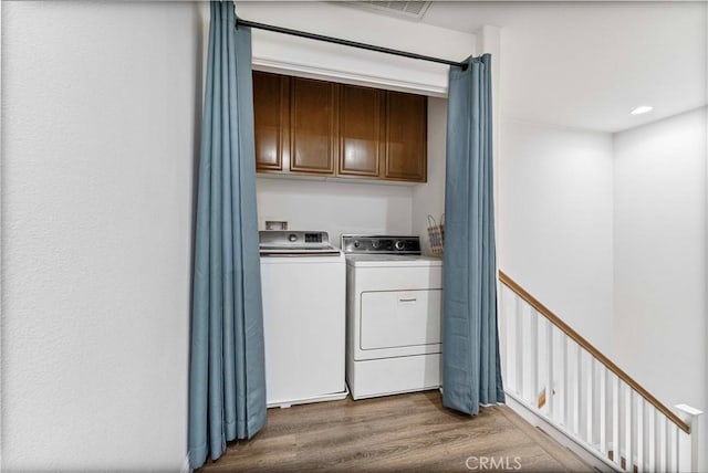 laundry area featuring cabinet space, washer and clothes dryer, and wood finished floors