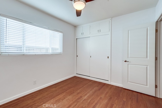 unfurnished bedroom with light wood finished floors, a ceiling fan, baseboards, and a closet