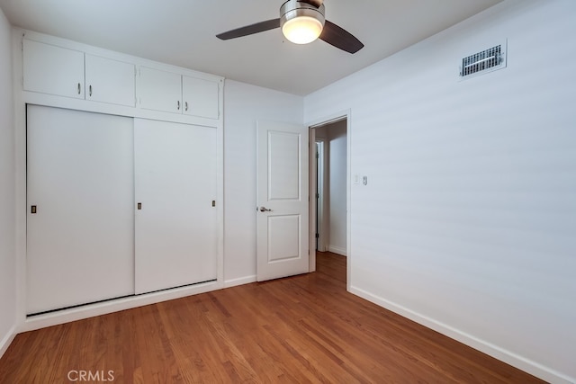 unfurnished bedroom featuring a closet, visible vents, light wood-style floors, ceiling fan, and baseboards