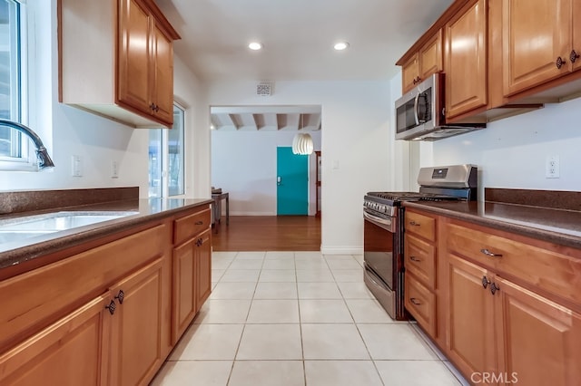 kitchen with light tile patterned floors, dark countertops, recessed lighting, appliances with stainless steel finishes, and a sink