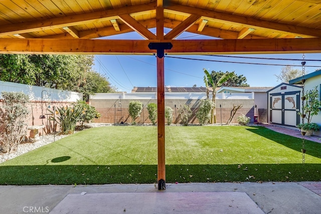 view of yard with an outbuilding, a fenced backyard, and a storage unit