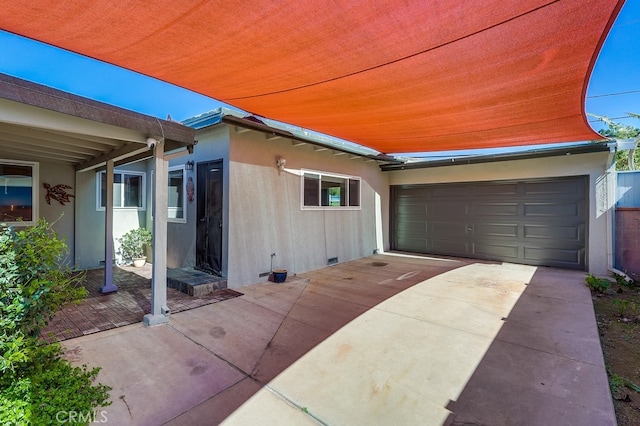 exterior space with a garage, crawl space, driveway, and stucco siding